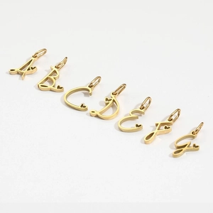 Close-up of golden A-G alphabet charms with tiny heart details on white background