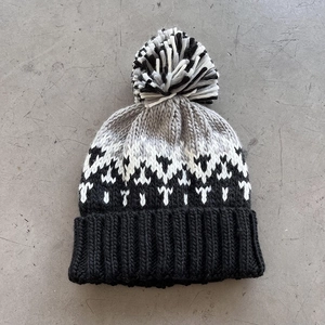 Macro view of knit texture with geometric jacquard pattern and a soft bicolor pom-pom