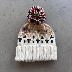 Detail of knit beanie with colorful pompom and geometric diamond jacquard texture