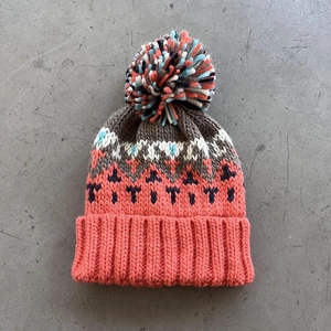 Detail of multi-color knitted beanie with geometric pattern and fluffy pom-pom top