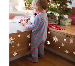 Toddler footie pajama with pink and blue stripes in a festive Christmas home setting