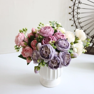 Close-up of pink and purple faux peonies and roses in a white ceramic striped vase