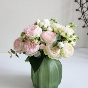 Detailed view of pink and beige silk peonies in a green ribbed glass vase for home decor