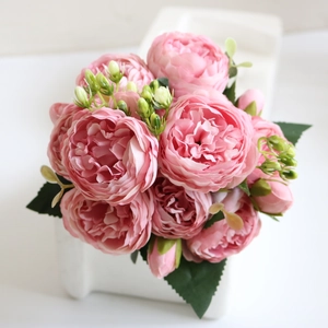 Close-up of pink artificial peonies and green buds in a white ceramic vase decoration
