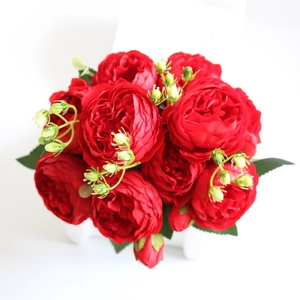 Overhead macro view of artificial red peony rose bouquets with green buds and leaves
