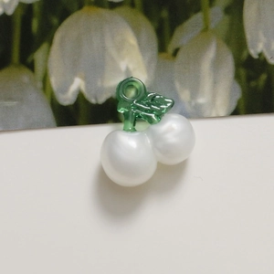 Macro shot of white pearl cherry charms with green translucent stems for DIY jewelry