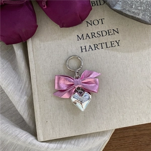 Detail of pink metal bow and silver heart pendant on vintage books for accessories