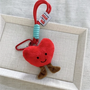 Dettaglio portachiavi a cuore in peluche rosso con viso sorridente e moschettone