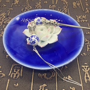 Detail of a Chinese style blue and white ceramic hair pin with silver tassels and butterfly