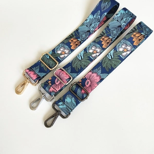 Detail of dark blue floral print bag straps with gold, silver and gunmetal hardware hooks