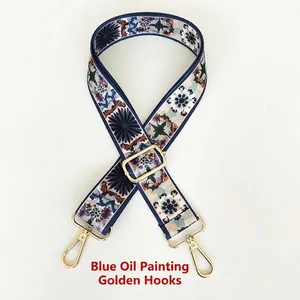 Close-up of blue oil painting style bag strap with adjustable gold metal hooks