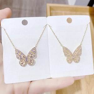 Close-up of gold-plated butterfly pendant necklaces with purple and pink cubic zirconia stones
