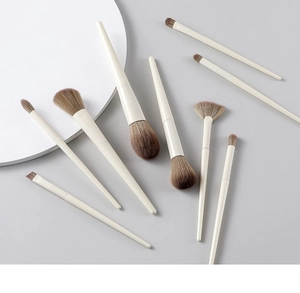 Detail shot of soft beige makeup brushes with brown gradient bristles on a gray surface