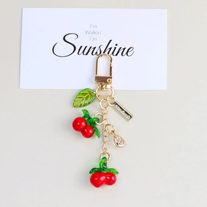 Cute cherry resin keychain with green leaves and a golden handmade tag on a gift card