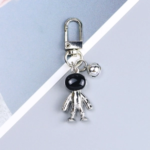 Detailed shot of silver astronaut keychain with black visor and silver bell attachment