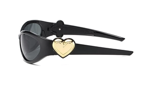 Detail view of black frame sunglasses featuring a bold golden heart on the wide temple