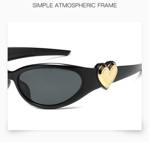 Close-up of black y2k sunglasses showing gold heart hinge detail and polished frame