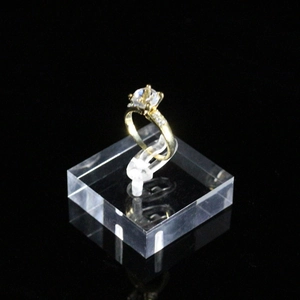 Elegant gold ring with large round solitaire gemstone on a clear acrylic display stand