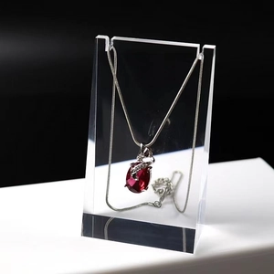 Detail of red oval gemstone pendant on silver chain hanging on acrylic display stand