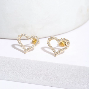 Fashionable gold heart stud earrings with white cubic zirconia pavé on a white pedestal