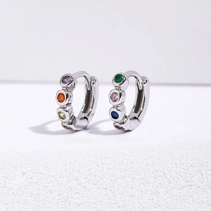 Minimalist silver hoop earrings with multicolored round gemstones on a white display