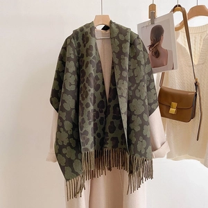 Detail of army green leopard print cashmere scarf with tassels on a hanger