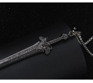 Macro shot of silver sword pendant with vintage engravings and winged hilt on black leather