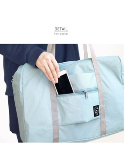 Detail view of the front zipper pocket on a light blue travel bag for phone storage
