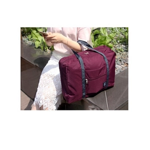 Outdoor view of a large burgundy waterproof travel bag with reinforced straps on a stone bench