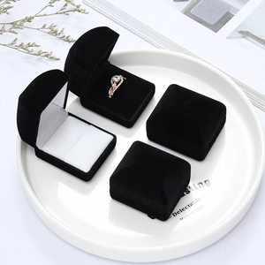 Detail of four black flocked jewelry boxes for rings and earrings on a white tray