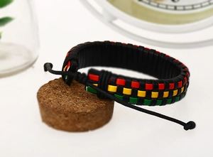 Detail of adjustable black leather bracelet with red, yellow, and green braided cord accent