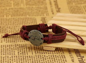 Detailed macro view of Gemini bronze charm on vintage braided leather zodiac bracelet