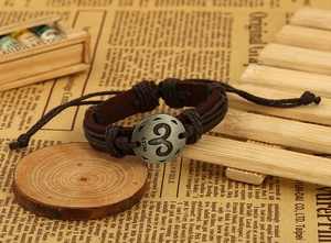 Macro shot of brown leather woven bracelet featuring a vintage metal Aries zodiac sign charm