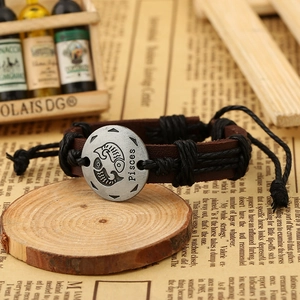 Macro shot of Pisces zodiac brown leather braided bracelet with silver metal charm