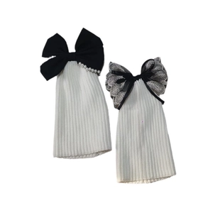 White ribbed knit leg warmers featuring black lace bows and elegant pearl accents