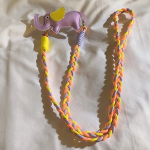 Detail of colorful woven phone lanyard with purple elephant charm and metal clasps