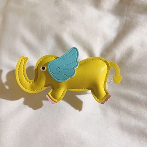 Detail of yellow elephant leather phone charm with blue wings and premium stitching