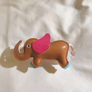 Detail view of a handcrafted brown leather elephant pendant with pink wings and blue feet