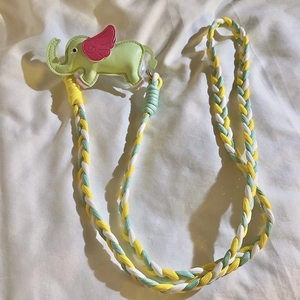 Close-up of woven yellow, white and green phone lanyard with a cute green elephant charm