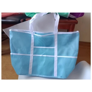 Detail view of a light blue mesh beach bag with white straps and multiple storage pockets
