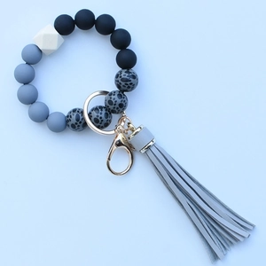 Close-up of leopard print silicone beads with grey tassel and golden keychain ring
