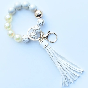 Close-up of leopard silicone beads and white PU tassel keychain with golden metal ring