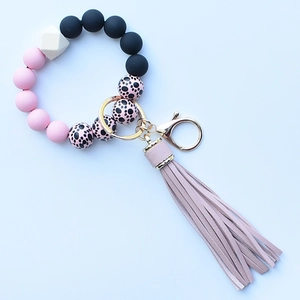 Detail of leopard print silicone beads and pink leather tassel on a gold keychain ring