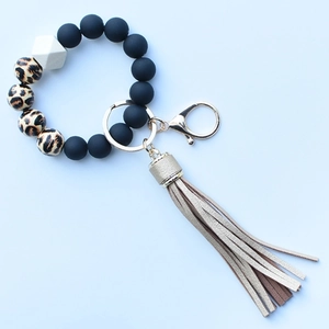 Detail of leopard print and matte black silicone beads with a golden fringe tassel keychain