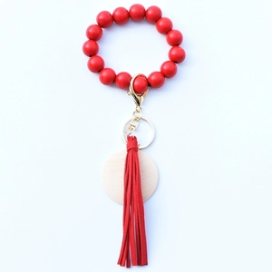 Detail of red bead bracelet keychain with leather tassel and wood disc on metal ring