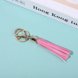 Pink PU leather tassel keychain with gold ring on a blue background with a book
