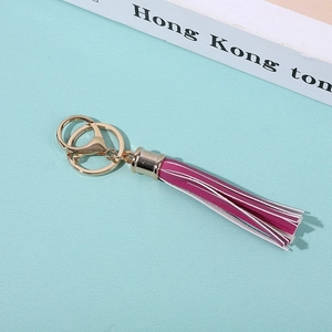 Macro shot of hot pink PU leather tassel keychain with gold metal clasp on blue background