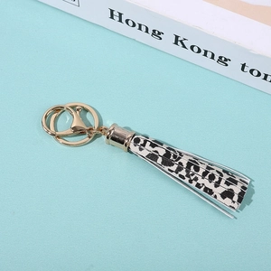 Close-up of leopard print tassel keychain with gold metal ring on a light blue background