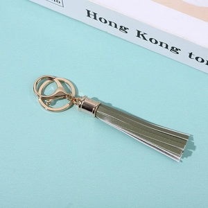 Close-up of green PU leather tassel keychain with polished gold metal hardware