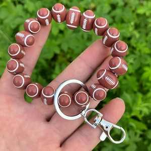 Detail of rugby-shaped wooden bead keychain with metallic silver ring and lobster clasp